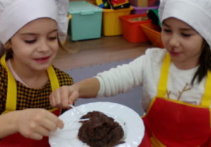 Dwie dziewczynki degustują budyń czekoladowy.